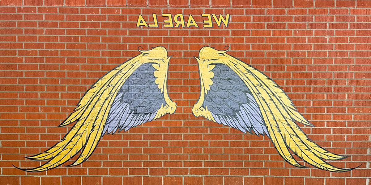 Artistic interpretation of wings on a white wall outside of the Cal State LA library..